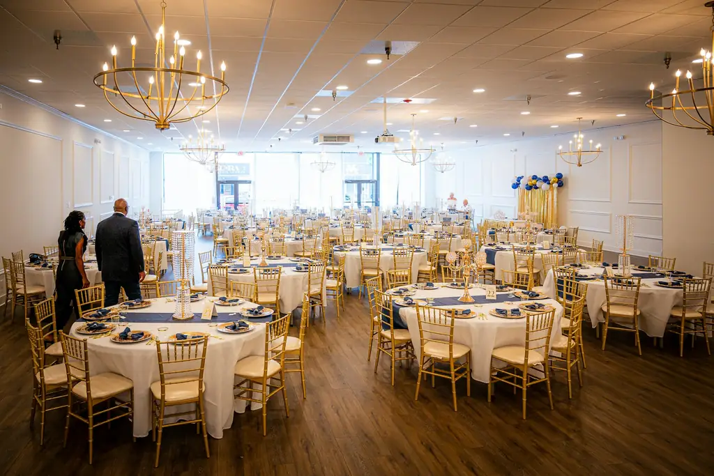 Salón de banquetes con mesas redondas preparadas para un evento.