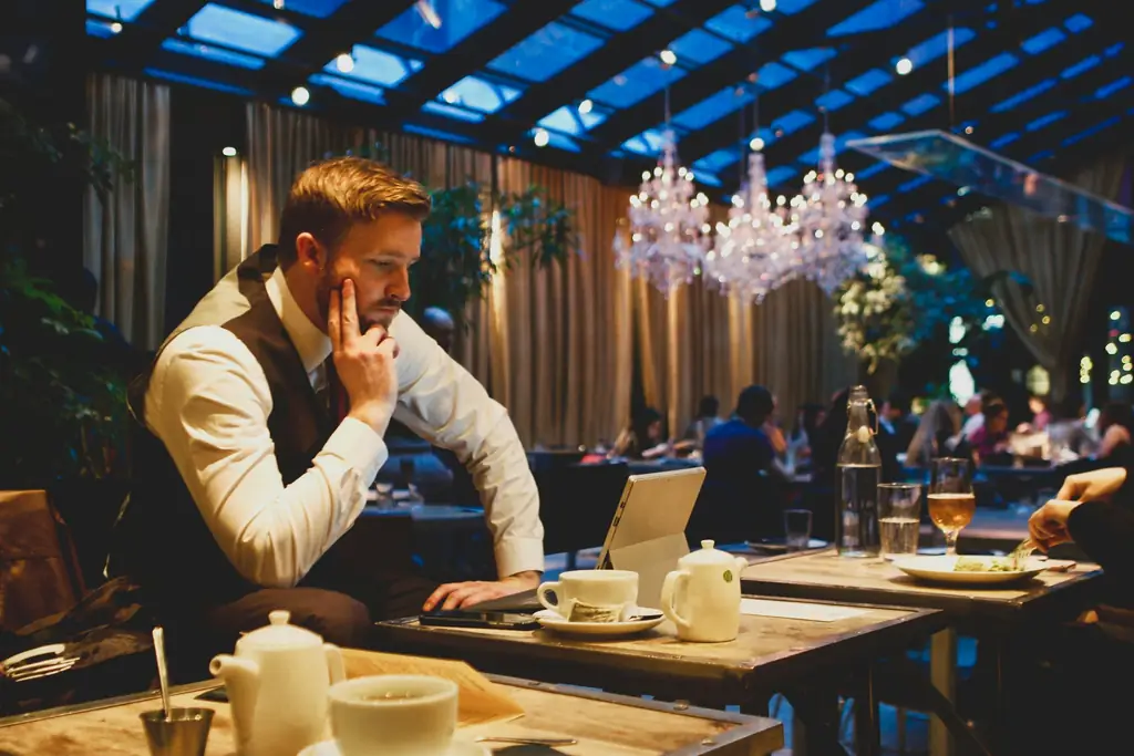 Un responsable revisa números con un portátil en la sala de un restaurante.