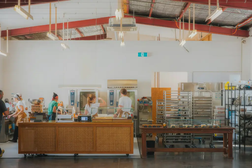 Cocina de producción con hornos y carros de bandejas.