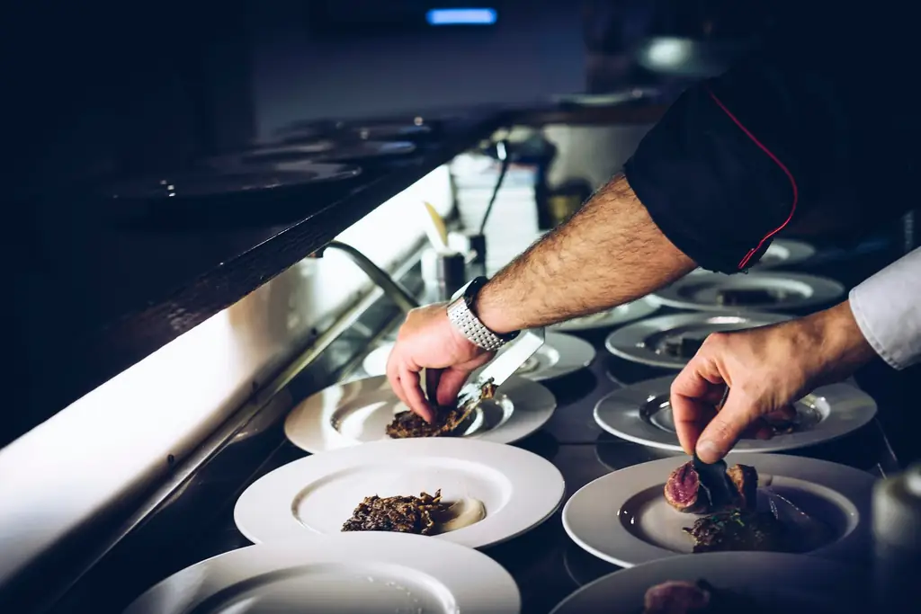 Un cocinero termina un plato en la cocina de un restaurante.